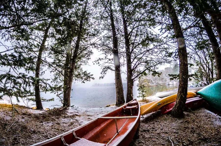 Photo of empty boats along the shore of a lake depicting a lonely winter in the outdoors.