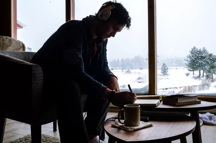 Person writing while listening to music against the snowy backdrop.